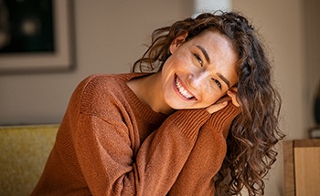 Woman in orange sweater leaning forward and smiling