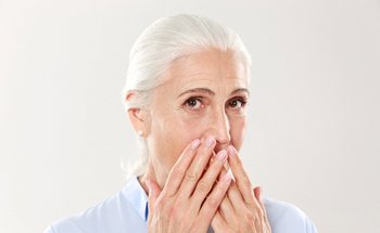older woman embarrassed covering mouth