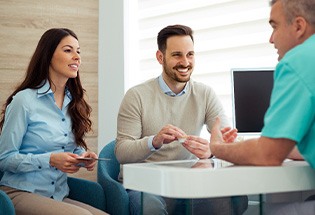 Dentist and couple talking in dental office