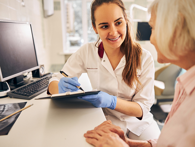 Dental team member listening to a patient and taking notes on a clipboard