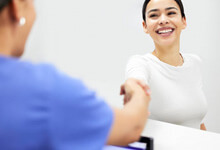 a woman smiling and shaking a persons hand