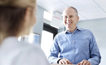 A patient smiling at a dental employee