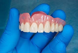 Close up of dentist holding an upper denture