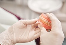 Dental lab technician carefully holding dentures