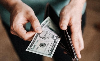 Close up of man’s hands pulling cash out of wallet