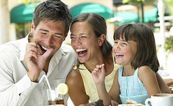 Laughing mother father and daughter eating dessert