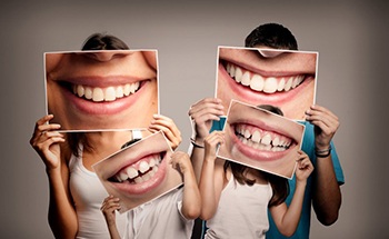 family of four holding pictures of their smiles in front of their faces 