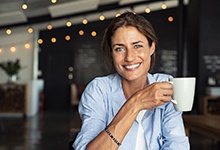 woman in a coffee shop holding a white mug 