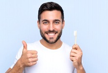 Man with dental implants in San Antonio holding toothbrush