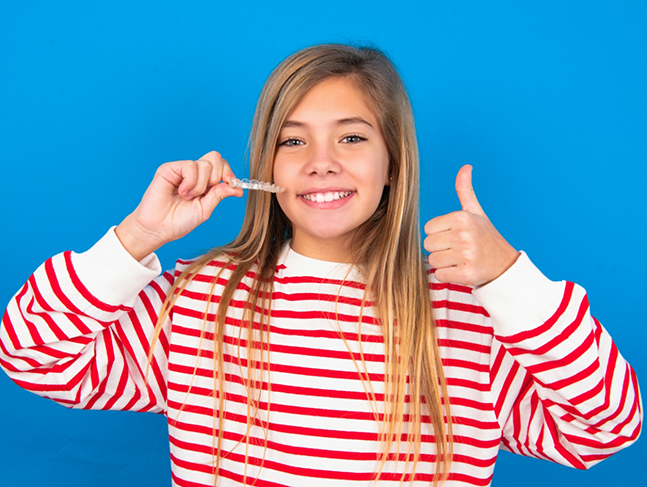 Teen girl holding Invisalign and giving a thumbs up