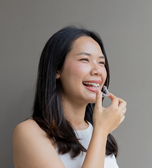 Woman placing Invisalign over her upper teeth