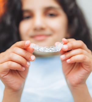 Woman in the dental chair holding Invisalign