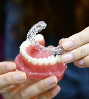 Dentist placing Invisalign over a model of the teeth