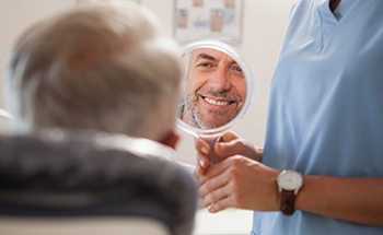 Man smiling at reflection in handheld mirror