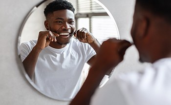 Dentist examining patient's teeth
Man smiling while flossing his teeth in bathroom
