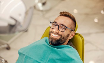 Man with glasses smiling while sitting in treatment chair