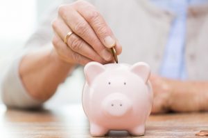 person putting coin into piggy bank