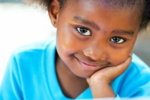 little girl smiling holding cheek