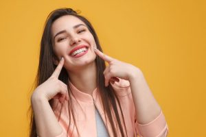 Woman pointing to her smile.